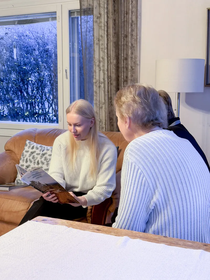 Helpen avustaja keskustelee ikäihmisen kanssa sohvalla